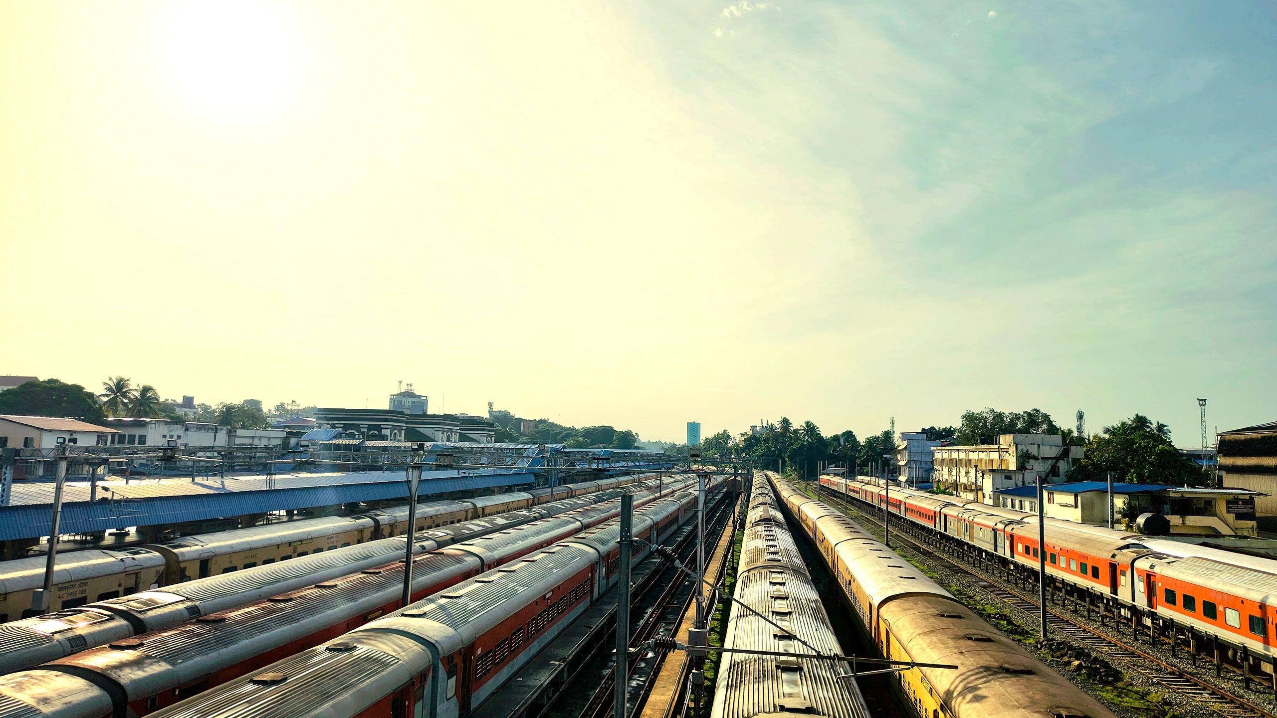 Multiple passenger trains on parallel tracks at a busy railway yard