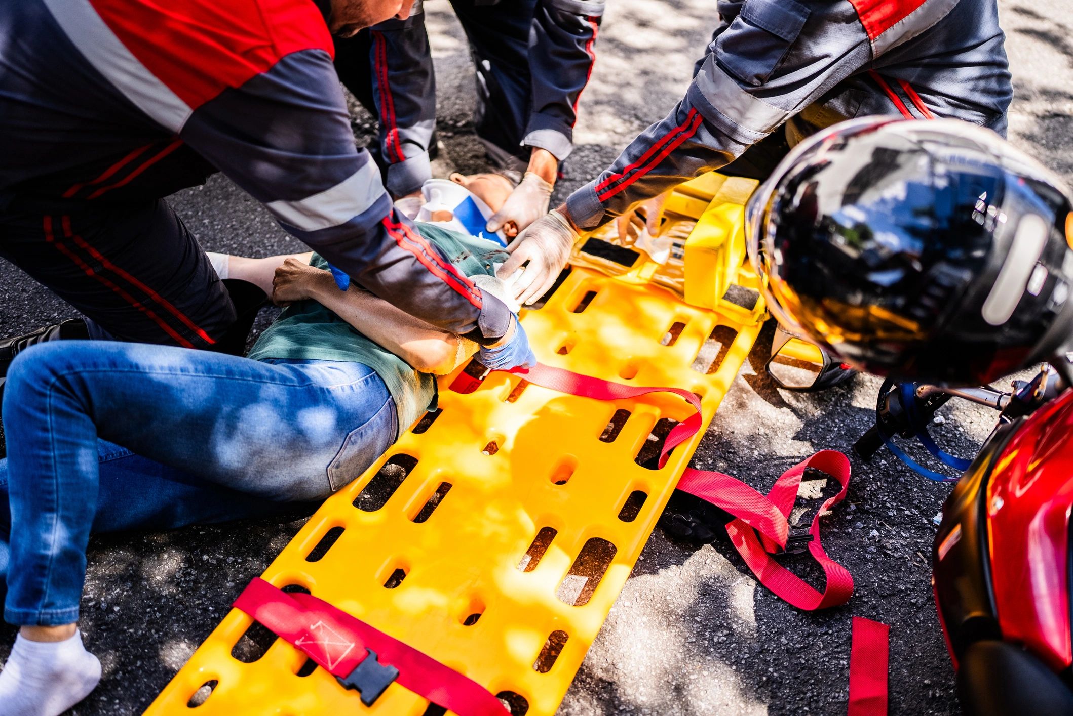 Emergency responders providing trauma care to a patient on a stretcher outdoors