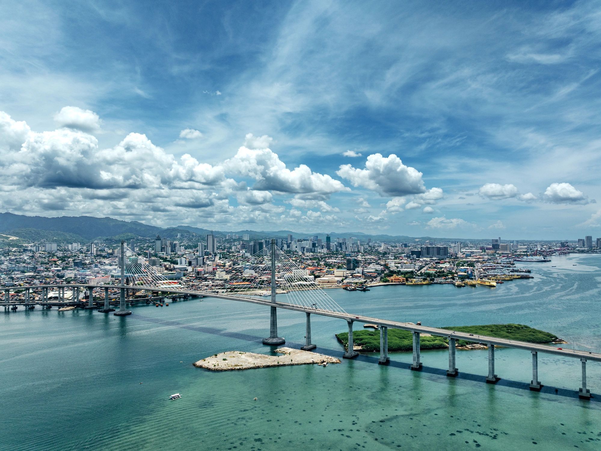 Aerial view of a busy coastal port with bridge and ships