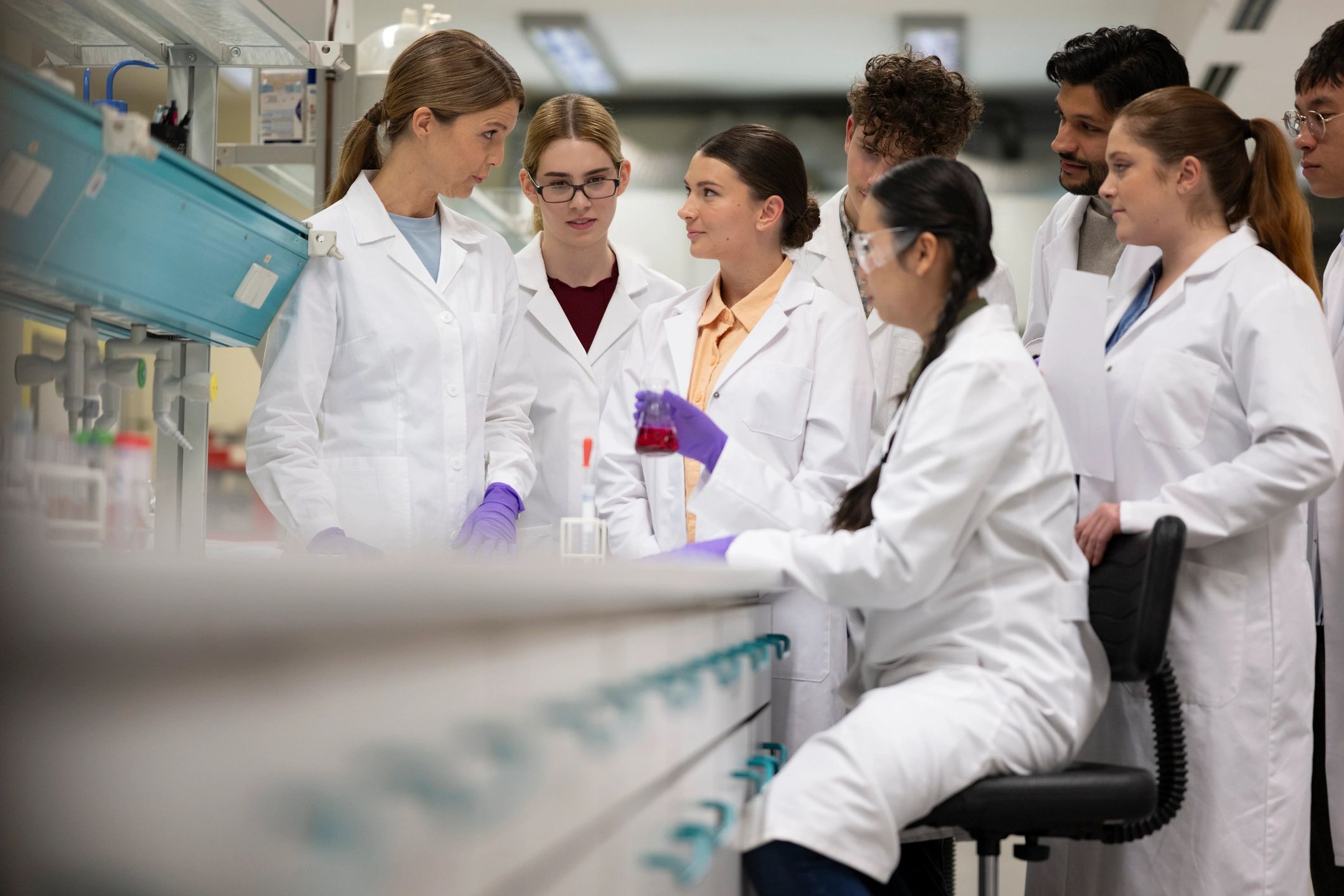 Professor guiding a diverse science team in a laboratory